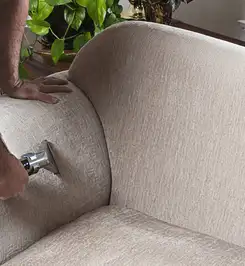 Professional upholstery cleaner deep-cleaning a fabric sofa with a handheld extraction tool and hose Colorado Springs, CO.